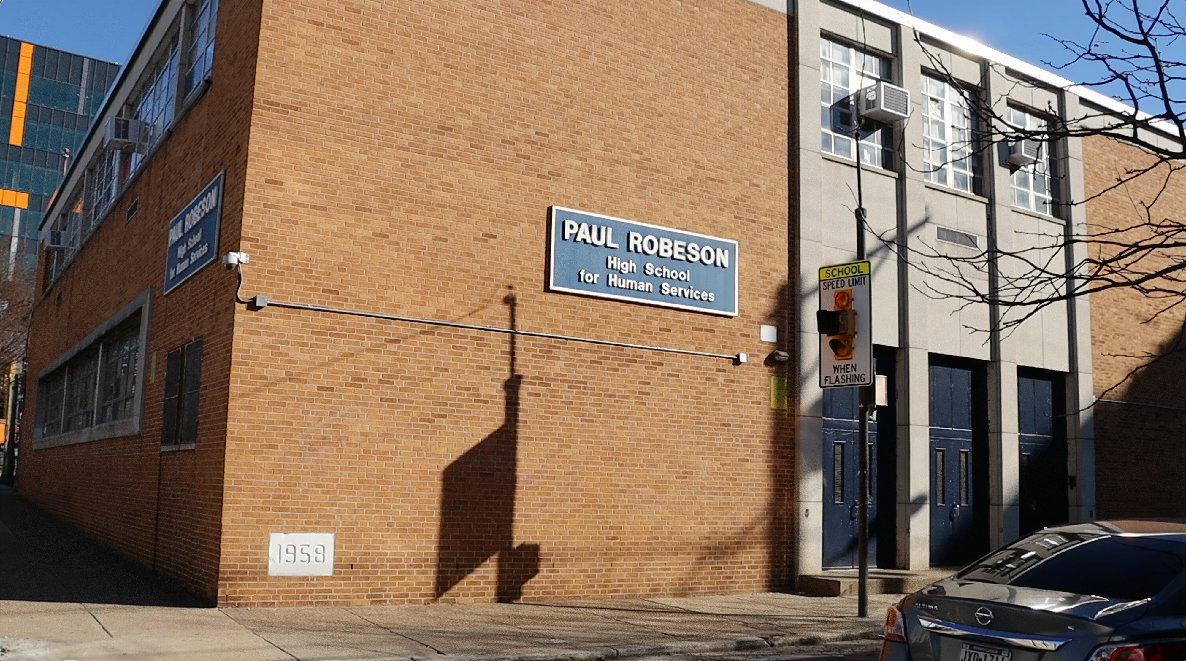 A brick school with a sign on the front reading, "Paul Robeson High School for Human Services."."