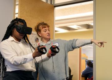 April Anson instructs a participant on using the VR headset and controls