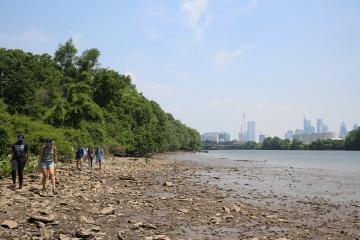 view of the schuylkill river with students on the rocky river bank in the bottom left corner